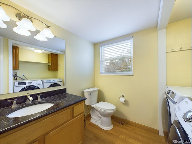 bathroom with toilet, wood finished floors, visible vents, vanity, and washing machine and clothes dryer