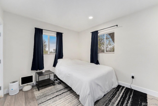 bedroom with baseboards, recessed lighting, wood finished floors, and multiple windows