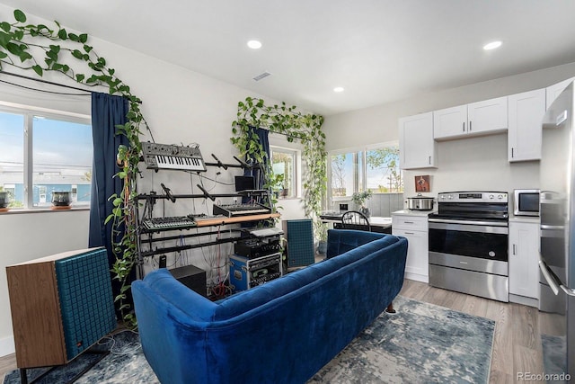 living area with visible vents, recessed lighting, and light wood-type flooring