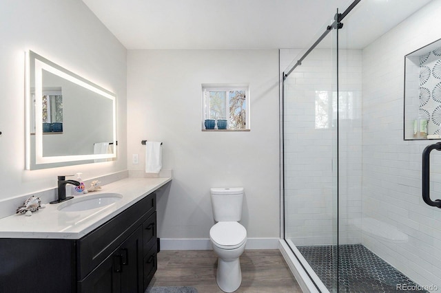 bathroom featuring a shower stall, wood finished floors, vanity, baseboards, and toilet