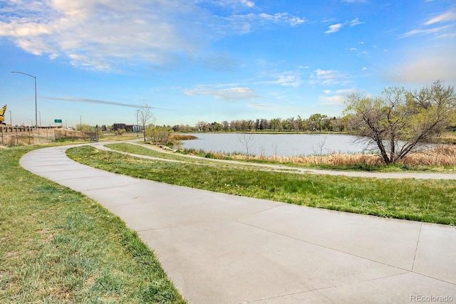 surrounding community with a water view and a yard