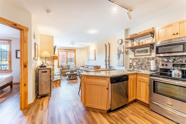 150 Dercum Sq Unit 8501, Keystone, CO 80435 - kitchen with open floor plan, backsplash, light wood finished floors, light brown cabinets, and appliances with stainless steel finishes
