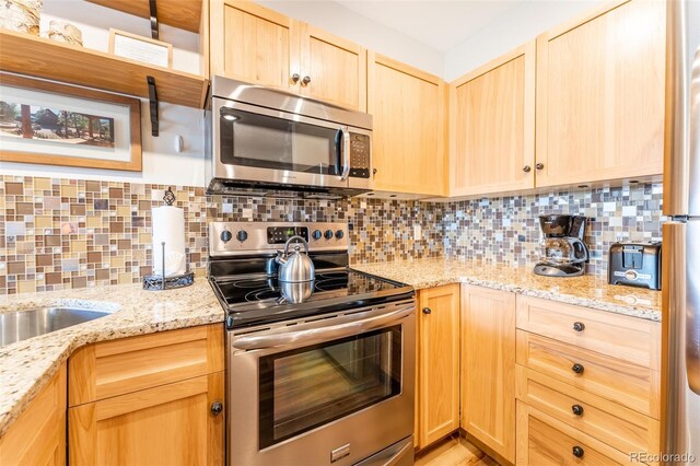 150 Dercum Sq Unit 8501, Keystone, CO 80435 - kitchen featuring light stone countertops, stainless steel appliances, backsplash, and light brown cabinetry