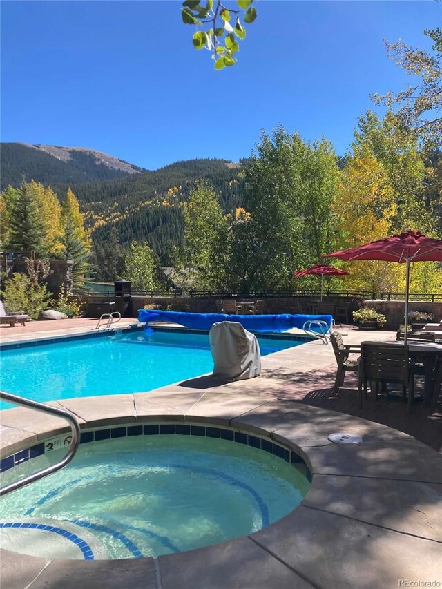 150 Dercum Sq Unit 8501, Keystone, CO 80435 - view of pool with a fenced in pool, a forest view, an in ground hot tub, a mountain view, and a patio area