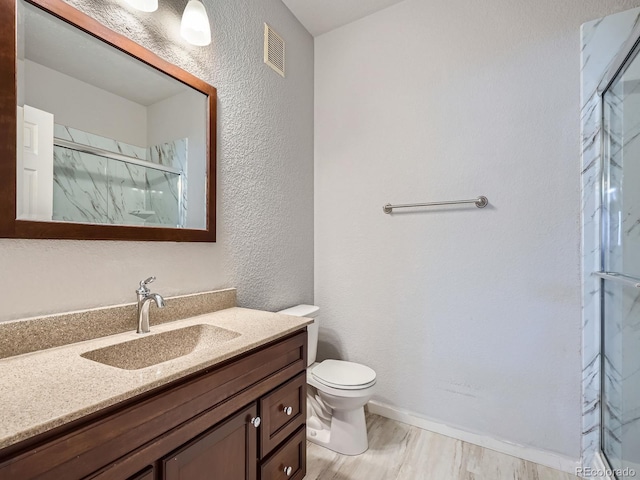 bathroom with toilet, hardwood / wood-style floors, vanity, and walk in shower