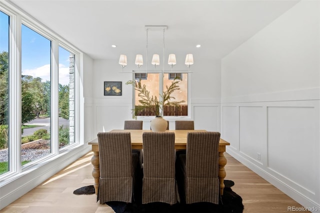 dining area with light wood-type flooring and a notable chandelier