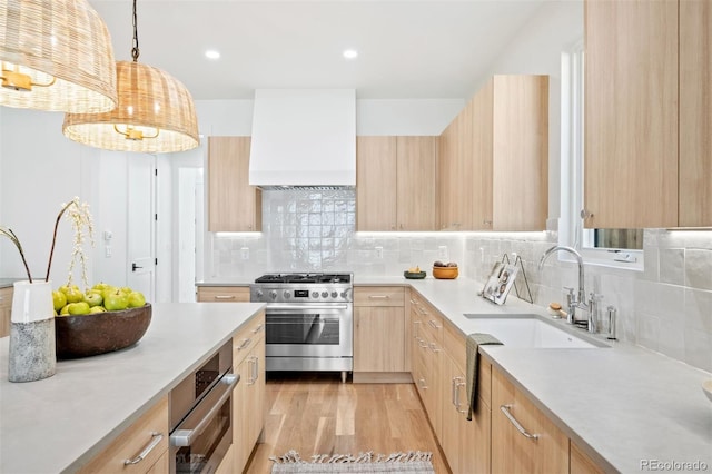 kitchen featuring custom range hood, stainless steel appliances, sink, light brown cabinets, and hanging light fixtures