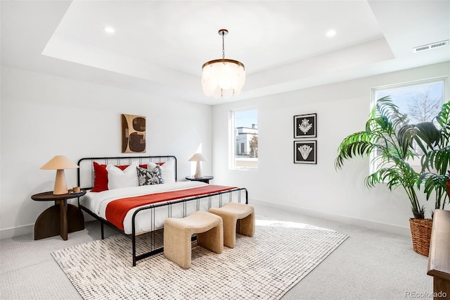 bedroom with a tray ceiling, visible vents, and baseboards