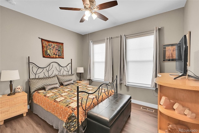 bedroom with hardwood / wood-style flooring, ceiling fan, and multiple windows