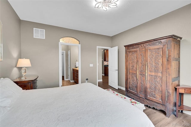 bedroom featuring hardwood / wood-style flooring and ensuite bath