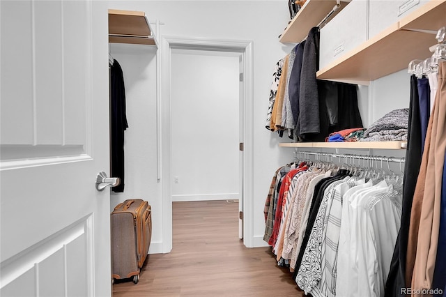 walk in closet with light hardwood / wood-style floors