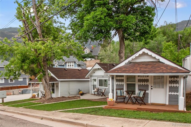 517 Canon Ave, Manitou Springs, CO 80829 - view of front of home featuring a porch, roof with shingles, a front lawn, and a mountain view