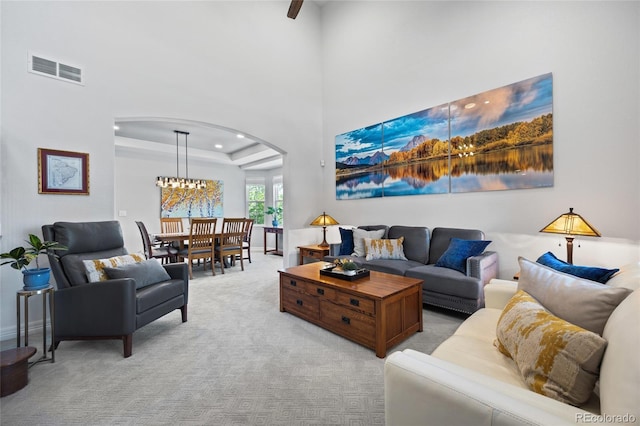 living area with an inviting chandelier, visible vents, arched walkways, and light carpet