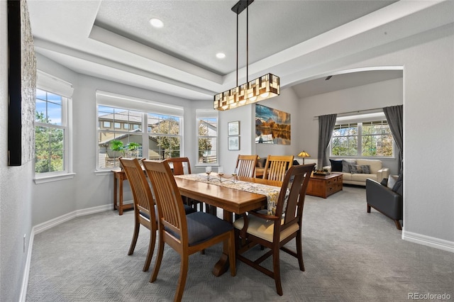 carpeted dining room featuring a raised ceiling, baseboards, arched walkways, and recessed lighting