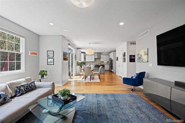 living area with light wood-style floors, visible vents, and recessed lighting