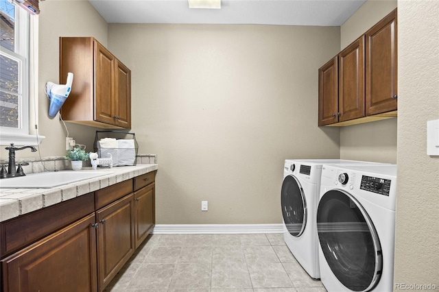 laundry area featuring plenty of natural light, cabinet space, a sink, and washer and clothes dryer