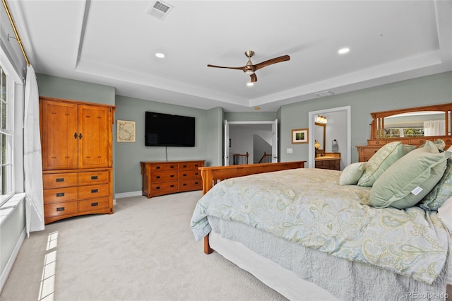 bedroom with a tray ceiling, recessed lighting, visible vents, and light colored carpet