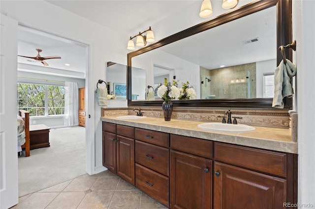 full bath featuring double vanity, visible vents, a tile shower, and a sink