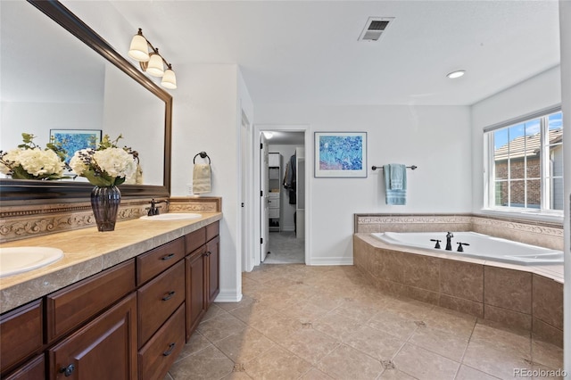 full bathroom with double vanity, a garden tub, tile patterned floors, and a sink