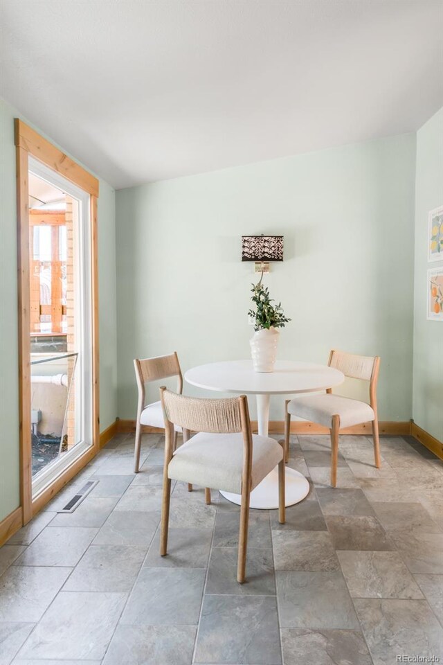 dining space with stone finish flooring and baseboards