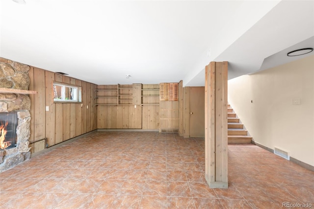 unfurnished living room featuring wood walls, stairs, and a fireplace