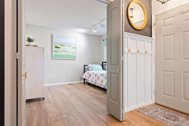 7 Shetland Ct, Highlands Ranch, CO 80130 - bedroom featuring light wood-style floors, a textured ceiling, rail lighting, and baseboards