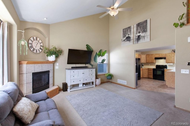 1275 W 50th St, Loveland, CO 80538 - living room with light carpet, a fireplace, ceiling fan, a high ceiling, and baseboards
