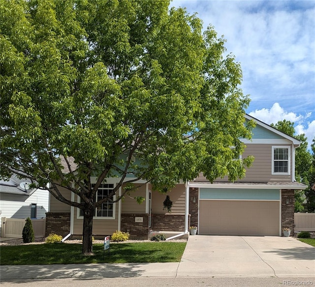 1275 W 50th St, Loveland, CO 80538 - view of property hidden behind natural elements featuring concrete driveway, brick siding, and an attached garage