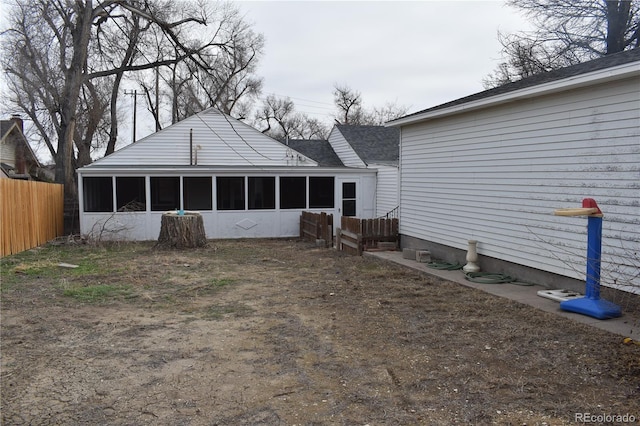 rear view of house featuring a sunroom and fence