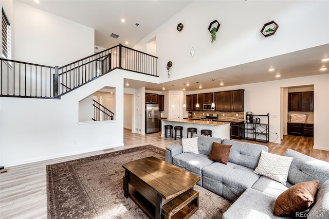 985 S Elk Way, Aurora, CO 80018 - living area featuring light wood finished floors, a high ceiling, stairway, and recessed lighting