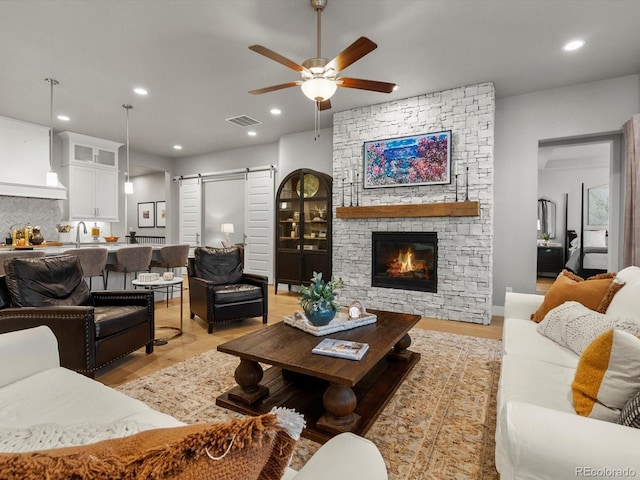 living area featuring visible vents, ceiling fan, light wood-type flooring, a barn door, and recessed lighting