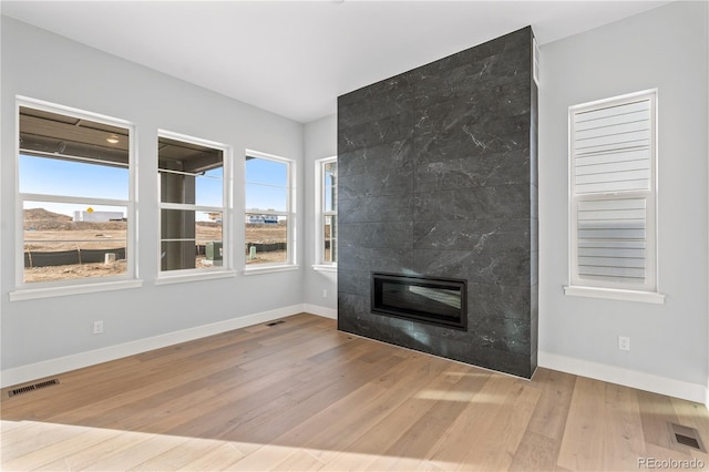 unfurnished living room with a wealth of natural light, a fireplace, and light hardwood / wood-style floors