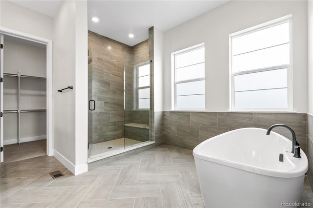 bathroom with tile walls and shower with separate bathtub