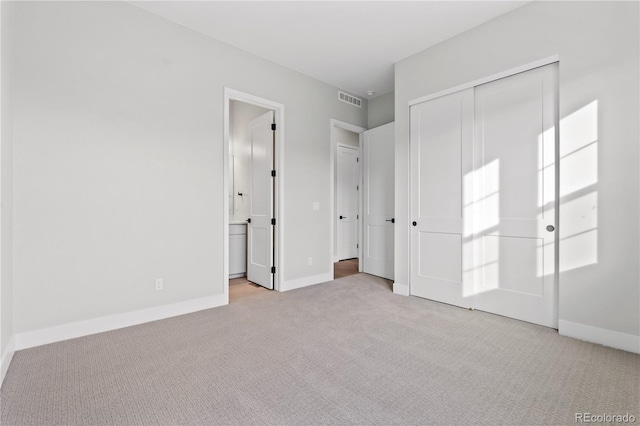 unfurnished bedroom with light carpet, connected bathroom, and a closet