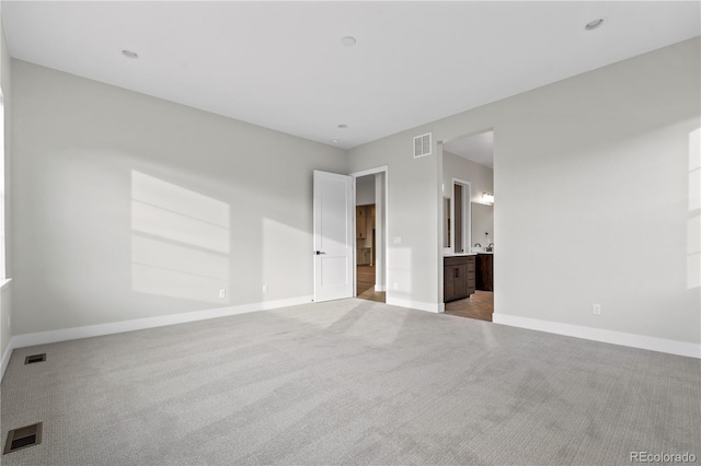 unfurnished bedroom featuring light colored carpet and connected bathroom