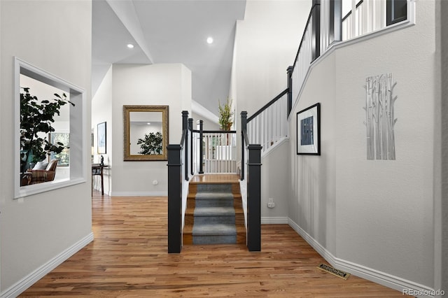 stairway with hardwood / wood-style flooring and a towering ceiling