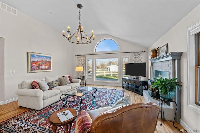 living room with a notable chandelier, vaulted ceiling, and light hardwood / wood-style floors