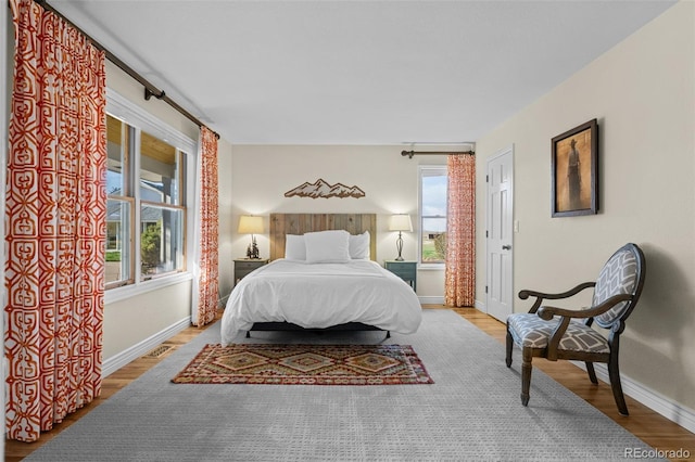 bedroom with multiple windows and light hardwood / wood-style flooring