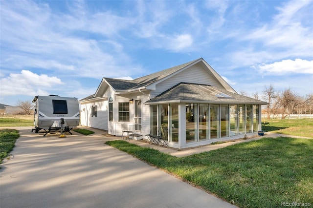 back of house featuring a sunroom and a lawn