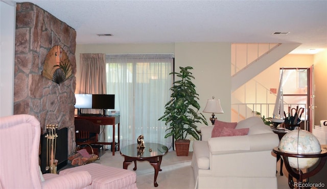 living room featuring a fireplace, a textured ceiling, and carpet flooring