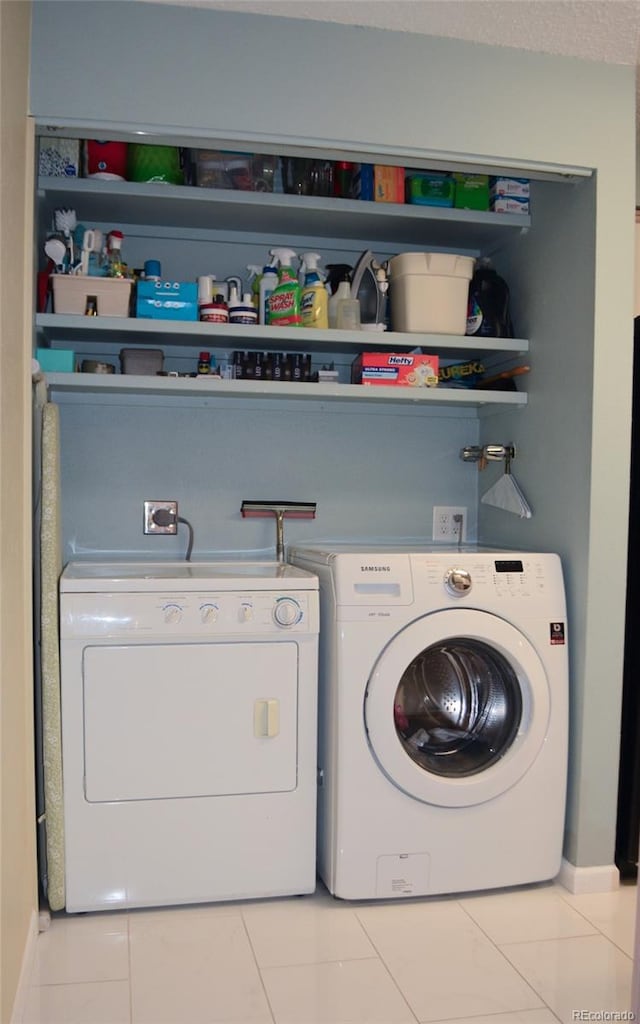 laundry area with washing machine and clothes dryer and light tile patterned flooring