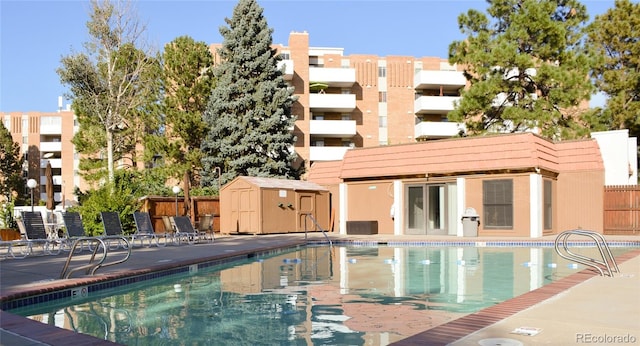 view of swimming pool with a shed and central air condition unit