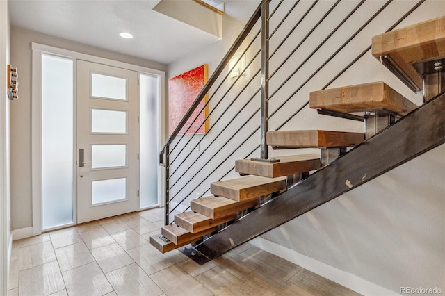 foyer entrance with stairs, recessed lighting, and baseboards