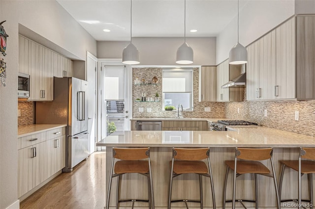 kitchen with appliances with stainless steel finishes, light countertops, a peninsula, backsplash, and modern cabinets