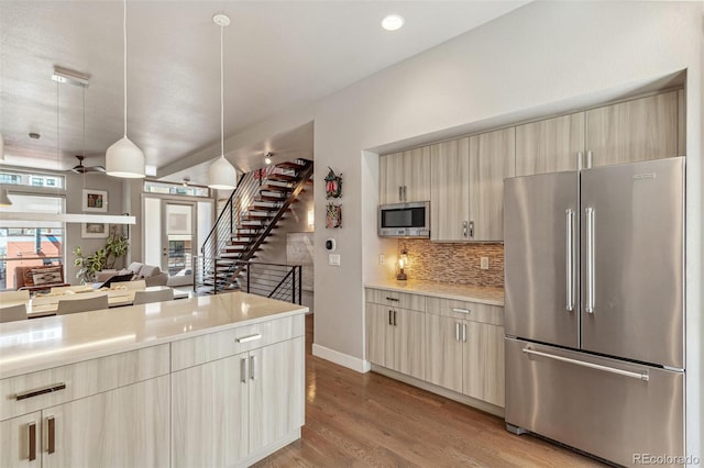 kitchen featuring decorative backsplash, open floor plan, light countertops, light wood-style flooring, and appliances with stainless steel finishes