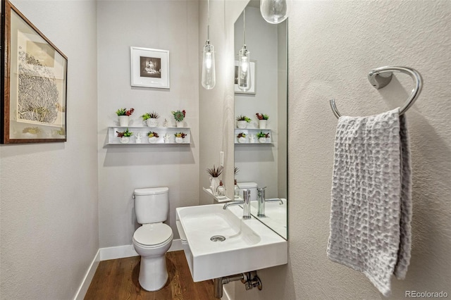 bathroom featuring a sink, baseboards, toilet, and wood finished floors