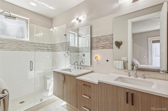 bathroom with tile patterned floors, two vanities, a sink, and a stall shower