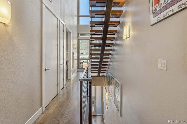 hall with baseboards, a textured wall, and wood finished floors