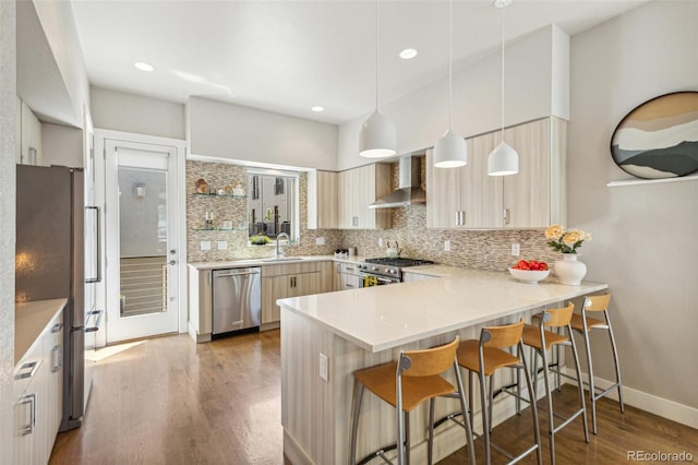 1012 Bannock St, Denver, CO 80204 - kitchen with appliances with stainless steel finishes, wall chimney range hood, backsplash, a peninsula, and wood finished floors