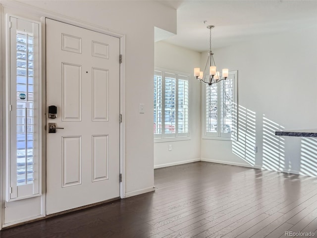 entryway with baseboards, dark wood finished floors, and a notable chandelier